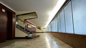 A spacious hallway with a marble floor, a wooden wall on one side, and a glass wall on the other. A staircase with a metal railing is visible in the center. - Roma Vaticano Deluxe Apartment, just steps from the Metro and St. Peter's (Roma)