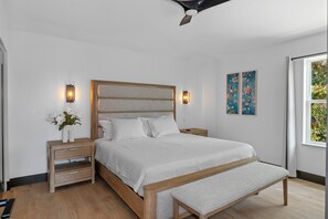 A bedroom with a large bed, bedside tables, a bench, and artwork on the wall. - Signature@TradeWinds Homosassa. Charming 3-bedroom villa, brand new, 2025 (Homosassa)