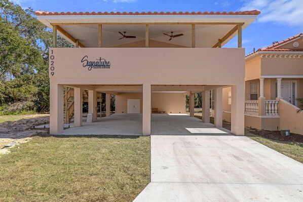 A two-story building with a covered patio area, a sign reading "Signature," and a number "10209" on the facade. - Signature@TradeWinds Homosassa. Charming 3-bedroom villa, brand new, 2025 (Homosassa)