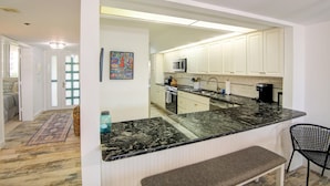 A kitchen with white cabinets, a black marble countertop, and a built-in oven. - Beachplace 3  - 302 by FGC (Longboat Key)