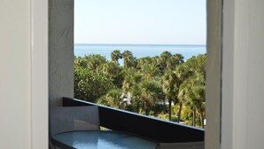 A balcony with a view of the sea and palm trees. - Partial Beach View 2 Bedroom Condo (Longboat Key)