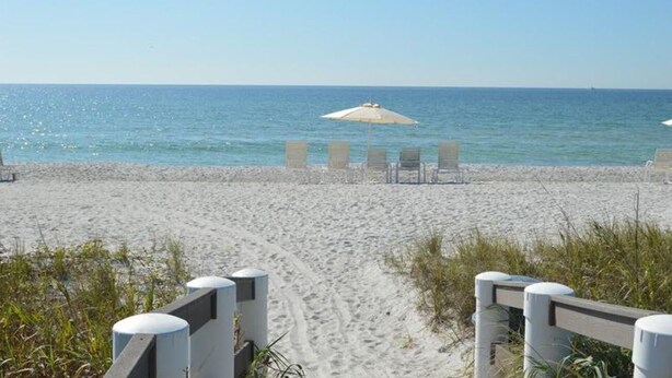 A beach with a sandy path leading to beach chairs and umbrellas. - Partial Beach View 2 Bedroom Condo (Longboat Key)