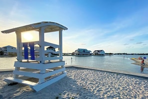 A lifeguard tower on a sandy beach with a water body in the background.