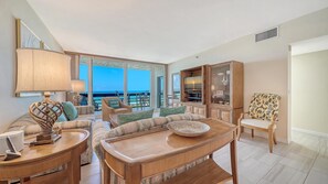 Amplia sala de estar con un ventanal grande, un televisor y un comedor con mesa y sillas.