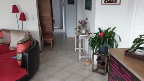 A living room with a sofa, a coffee table, and a TV stand. There is a hallway leading to another room. - Semi-detached house in the countryside garden covered terrace (Lahourcade)