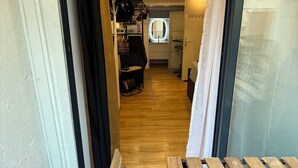 A narrow hallway leading to a room with a wooden floor, a bench, and a door with a sign that reads "BIENVENUE". - STUDIO COCON DeSIGN (Saint-André-les-Alpes)