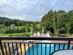A pool with a wooden deck and lounge chairs, surrounded by greenery and trees. - Gite des planchettes le hérisson (marigny)