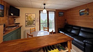 Una habitación acogedora con una mesa de comedor de madera, un sofá de cuero negro y un mapa en la pared.