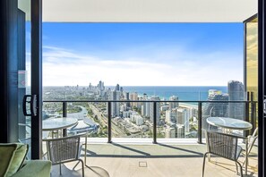 Enjoy breathtaking views of the city and ocean from this spacious balcony with a glass railing.