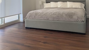 Ein Schlafzimmer mit einem großen Bett, Holzboden und einer Decke mit Einbauleuchten.
