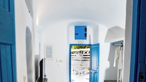 A room with a dining table set for two, a blue door, and a view of the outside.