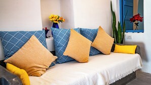 A sofa with patterned cushions, a vase with yellow flowers, and a plant.