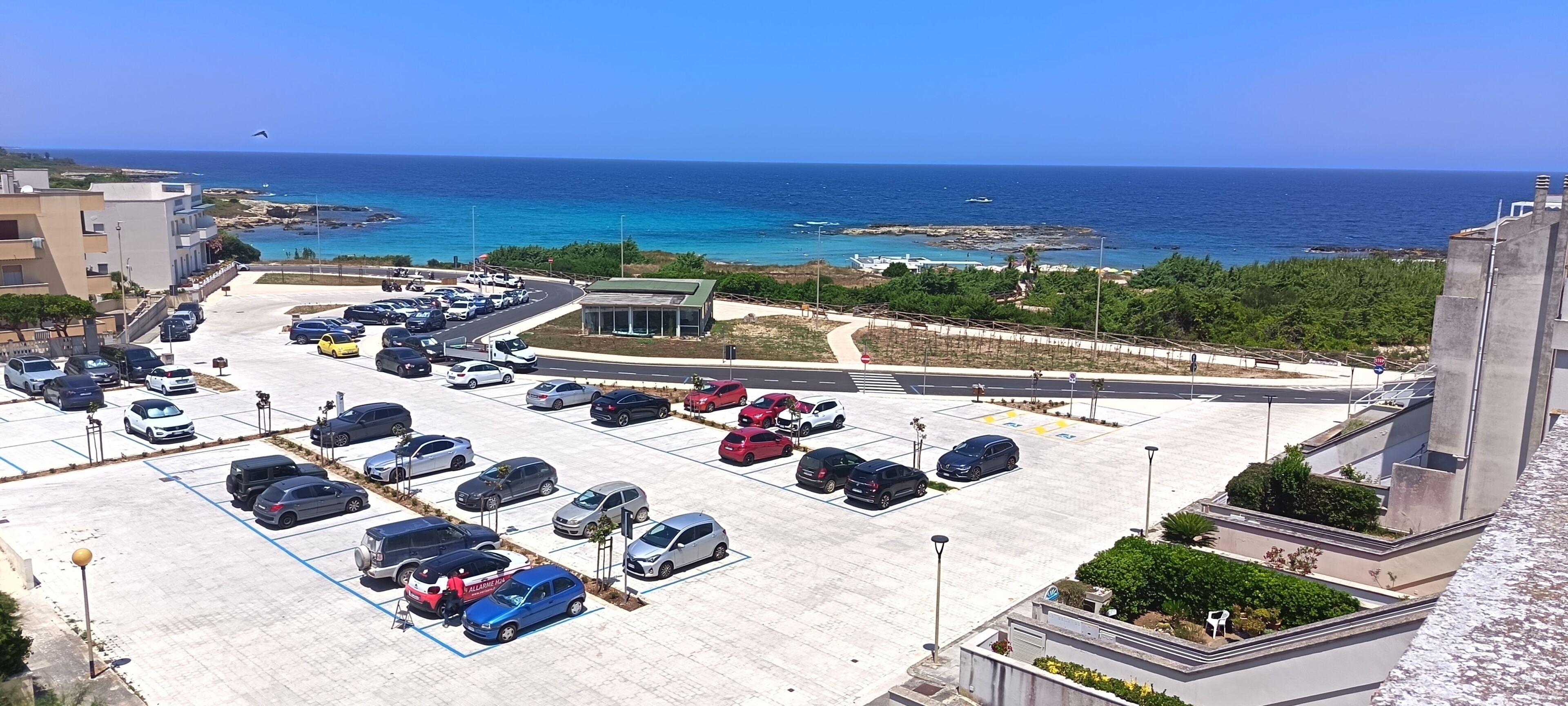 Un parking avec plusieurs voitures et une vue sur la mer.