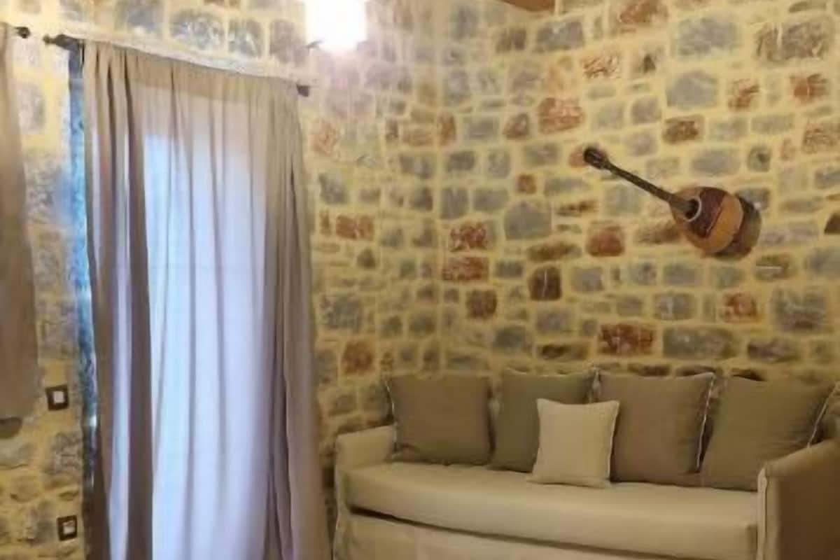 Ein Schlafzimmer mit Steinwand, einem Bett, einer Couch und einer Gitarre an der Wand.
