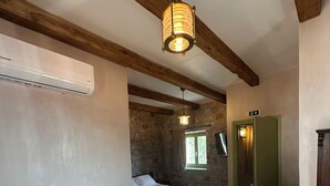 Una habitació acollidora amb un sofà blanc, un llit, una paret de pedra i una porta verda.