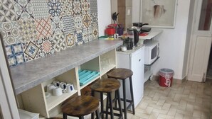 Una cocina con suelo de espiga, salpicadero de azulejos, microondas y taburetes de bar.