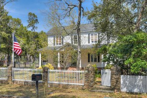 A two-story house with a front porch, a mailbox, and a white picket fence.