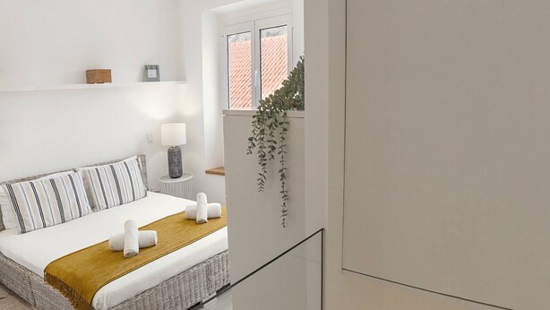 A modern bedroom with a bed, bedside table, and a view of the living area. - Fly House Nazaré - 3 minute walk to the beach (Nazaré)