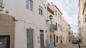 A cobblestone street lined with buildings, a narrow alley, and a parked car. - Fly House Nazaré - 3 minute walk to the beach (Nazaré)