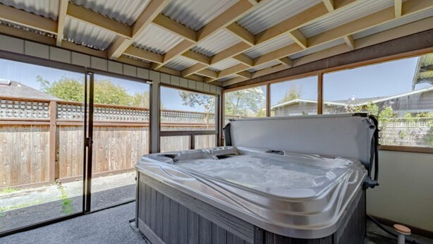 Un jacuzzi en un espacio exterior techado con techo de madera y ventanas amplias.