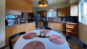 Una cocina moderna con armarios de madera, electrodomésticos de acero inoxidable y un comedor con una mesa redonda y posavasos.