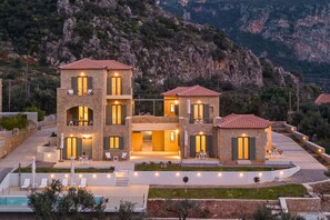 A modern multi-story building with a pool, outdoor seating, and a mountainous backdrop. - Ipso kardamyli Skinos (Kardamyli)