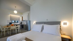 Een hotelkamer met een bed, een bureau en een kitchenette.
