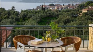 A terrace with wicker chairs and a table, overlooking a coastal town and mountains. - Ipso Kardamyli Mythies (Kardamyli)