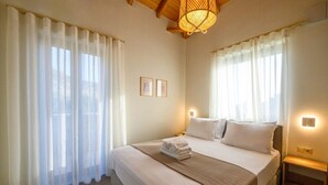 A hotel room with a large bed, white curtains, two wall-mounted lights, and a wooden ceiling. - Ipso Kardamyli Mythies (Kardamyli)