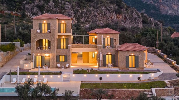 A modern multi-story building with a pool, outdoor seating, and a mountainous backdrop. - Ipso Kardamyli Mythies (Kardamyli)