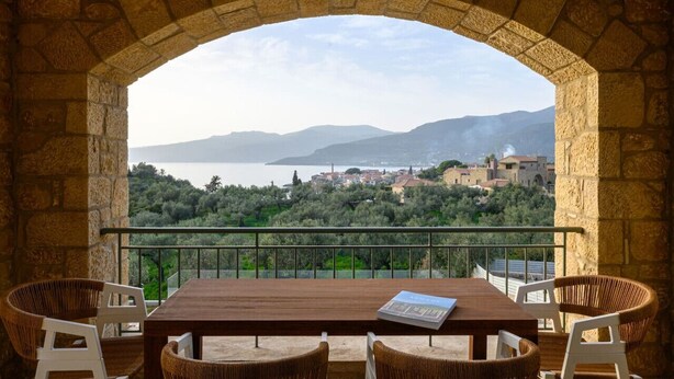 An outdoor dining area with a stone arch, wicker chairs, and a table. - Ipso Kardamyli Meropi (Kardamyli)