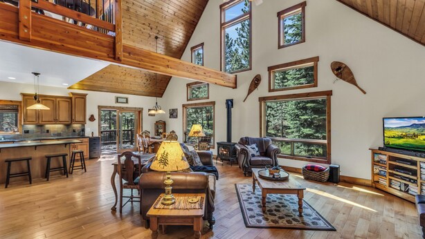 A spacious loft-style living area with high ceilings, large windows, and a cozy fireplace. - Beautiful 3 Bedroom Mountain Paradise near Lake Davis (Portola)