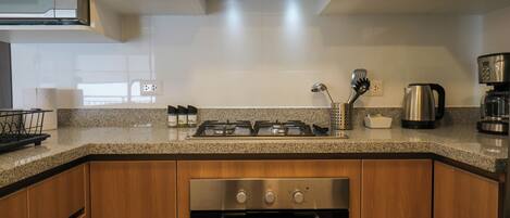 A kitchen with a microwave, stove, oven, and coffee maker.
