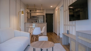 A modern living room with a sofa, a round coffee table, and a dining area with chairs and a table. - Aquilaria by Wynwood House  (Lima)