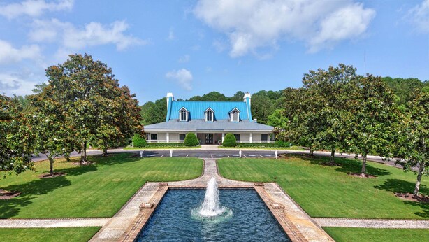 A large building with a blue roof, a central fountain, and a well-manicured lawn.