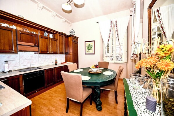 Una cocina con armarios de madera, una mesa de comedor con sillas y un jarrón con flores.
