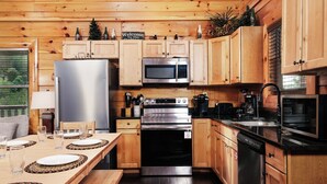 A wooden cabin-style kitchen with a refrigerator, microwave, stove, and dishwasher. - Time Well Spent - 10 Minutes from Parkway Attractions, Shops, Events & Food (Sevierville)