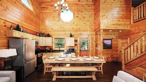 A wooden cabin interior with a kitchen, dining table, and seating area. - Time Well Spent - 10 Minutes from Parkway Attractions, Shops, Events & Food (Sevierville)