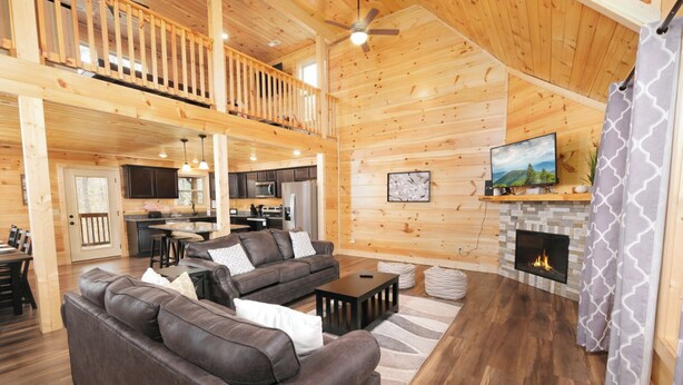 A spacious living area with a fireplace, wooden floors, and a balcony.