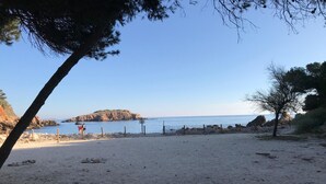 A beach with a rocky outcrop in the distance, a sandy path, and a fence along the water's edge. - Exceptional sea view, air conditioning, parking, private beaches, swimming pools, tennis court, marina. (Bandol)