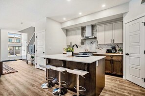 Une cuisine moderne dotée d’un îlot central, de tabourets de bar et d’un escalier menant à un niveau supérieur.
