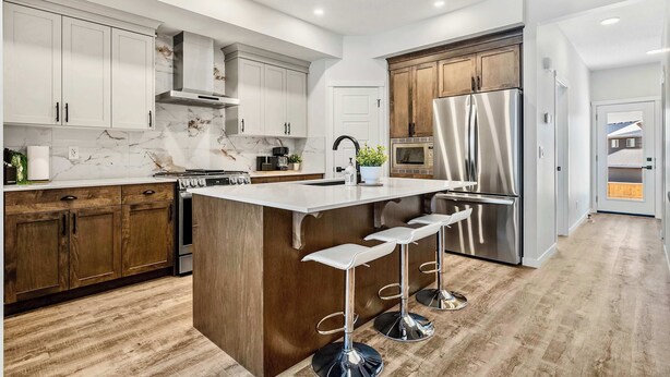 Una cocina moderna con una isla central, electrodomésticos de acero inoxidable y armarios de madera.