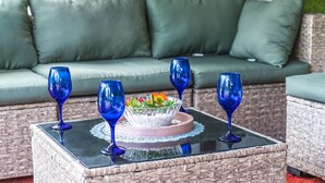 A wicker table with four blue glass tumblers and a bowl of fruit. - Charming Country Home, Pool, Pet Friendly (Clewiston)