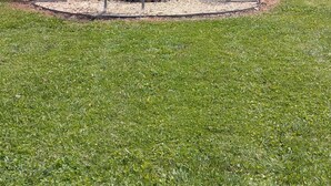 Un parque con tres sillas de metal y una pequeña mesa en el centro, rodeado por una zona circular de grava.