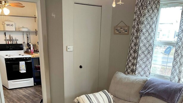 Una sala de estar con un sofá color beige, una mesa de centro de madera y una cocina al fondo.