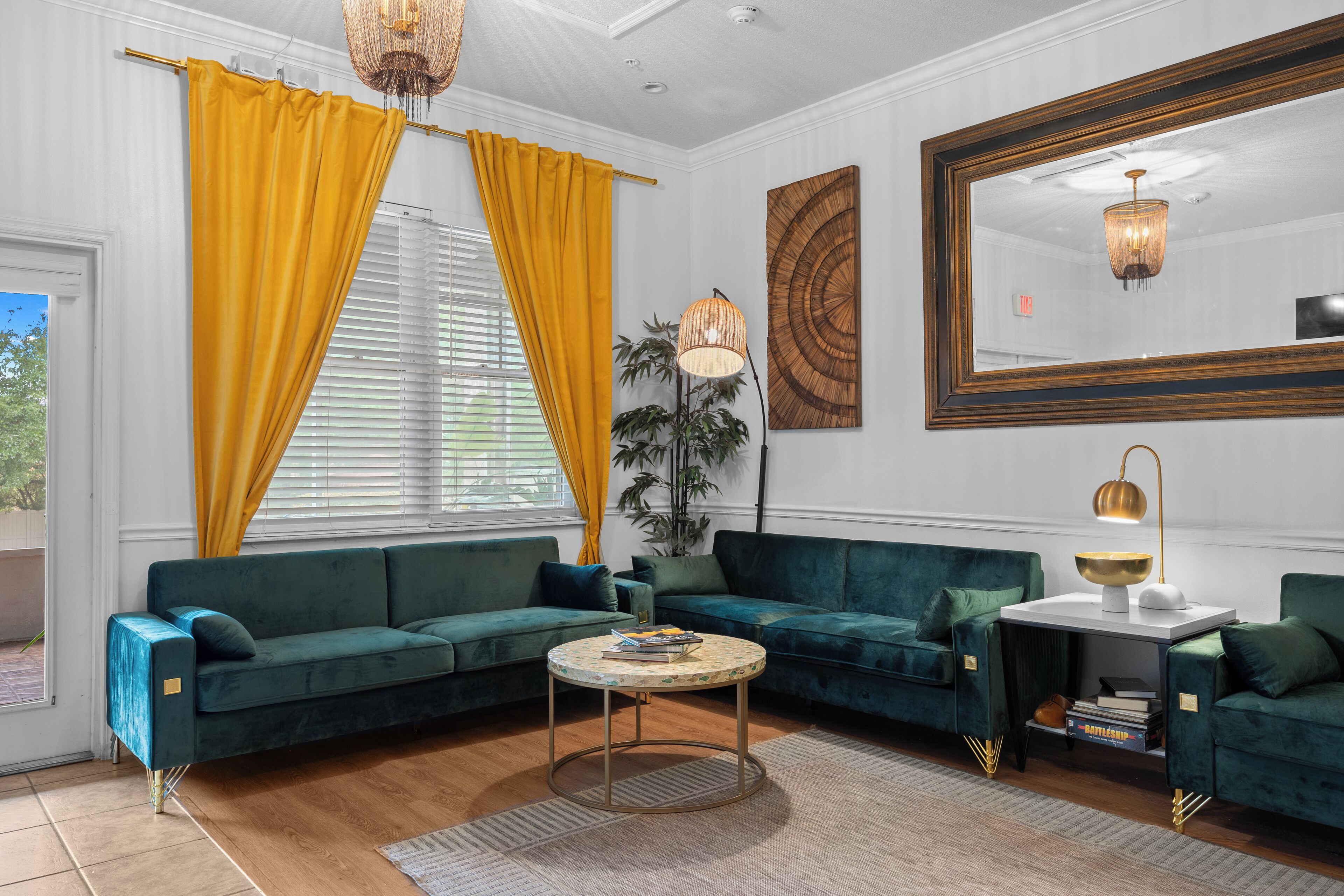 A modern living room with a green sofa set, a round coffee table, and a large mirror.