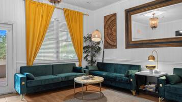 A modern living room with a green sofa set, a round coffee table, and a large mirror.