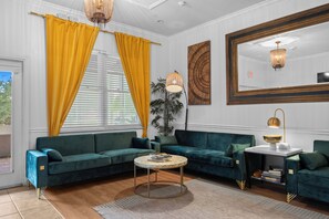 A modern living room with a green sofa set, a round coffee table, and a large mirror. - Banana Leaf Villa (Orlando)