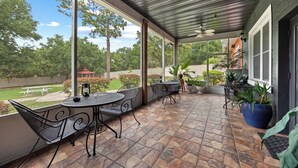 A covered patio with stone flooring, metal chairs, a table, and potted plants. - Banana Leaf Villa (Orlando)