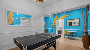 A room with a ping pong table, a mirror, a yellow chair, and a vase. - Banana Leaf Villa (Orlando)